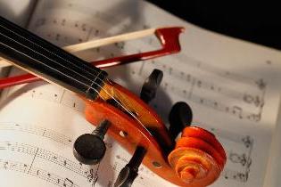 A violin and bow laying on a sheet of music.