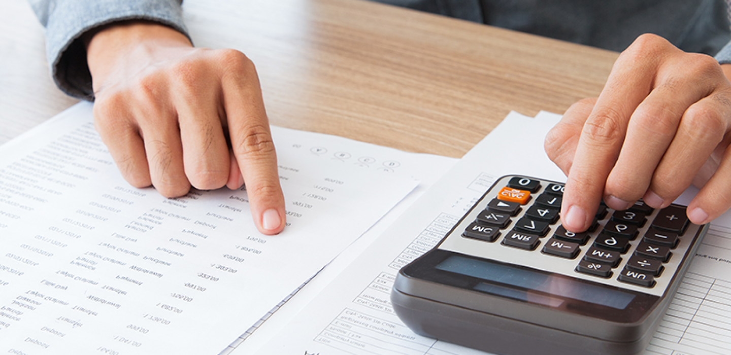 A person using a calculator while referencing financial documents.