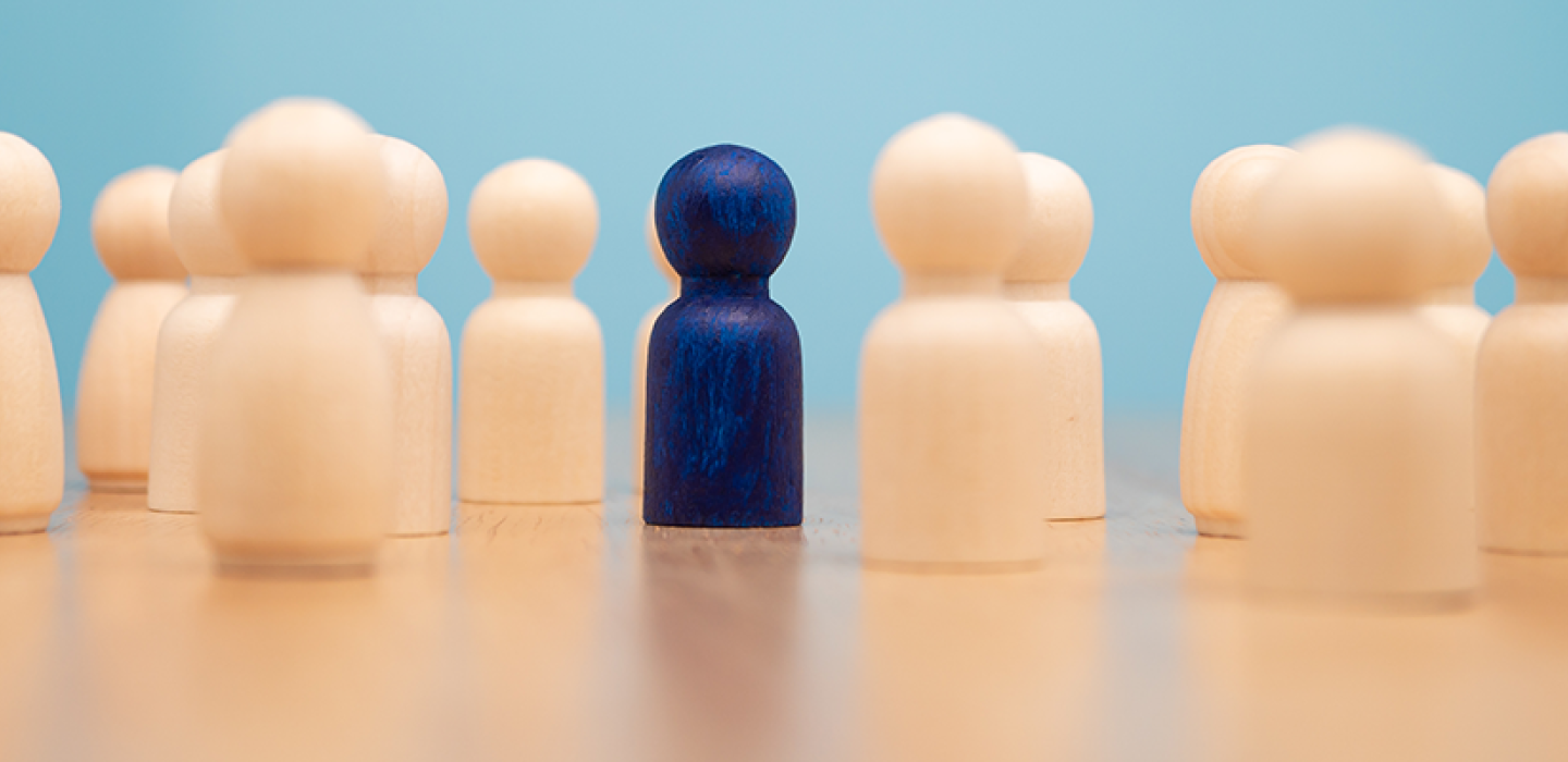 Wooden figure standing with team to show influence and empowerment